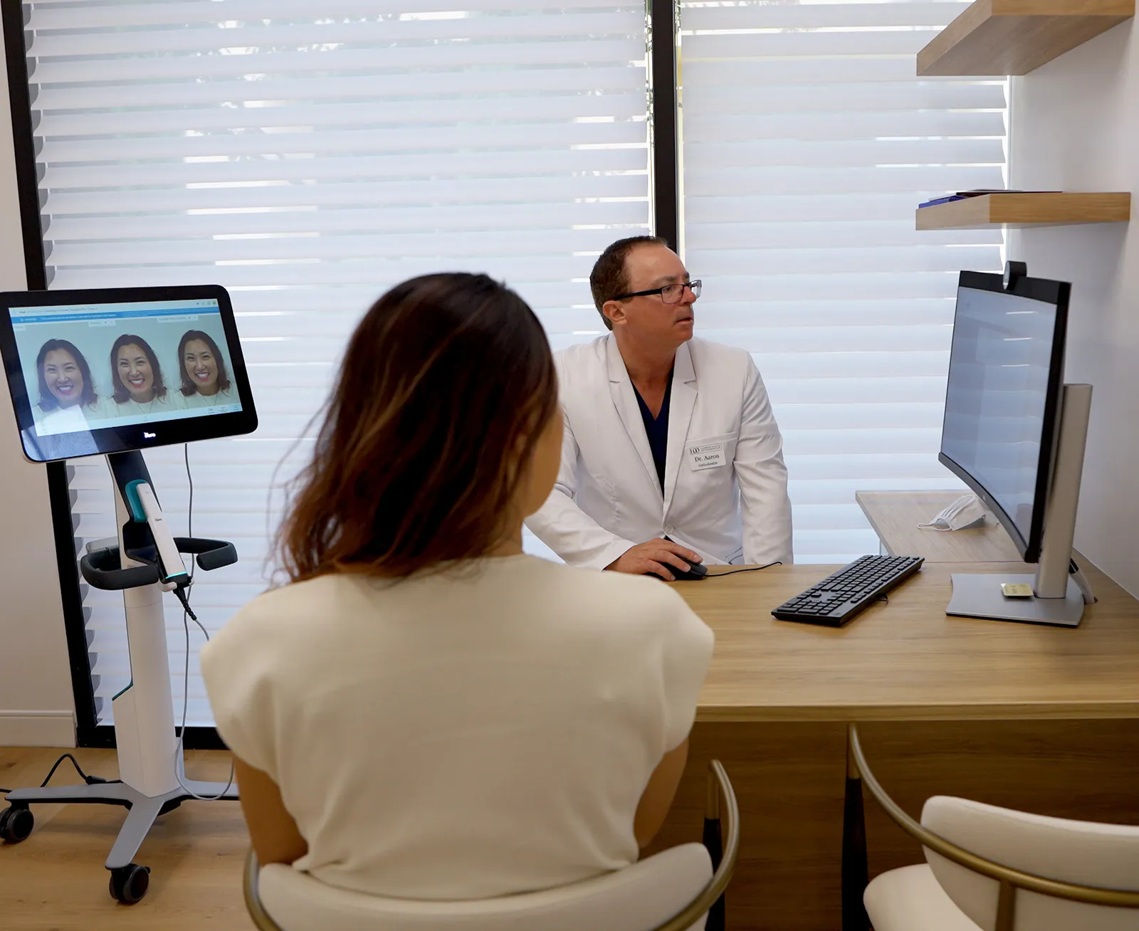 Orthodontist consulting with a patient at a desk with digital monitors
